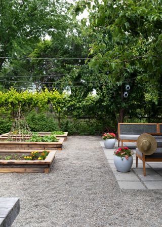 Backyard ideas on a budget, with a gravel yard, raised vegetable beds, a patio area and bench seating.