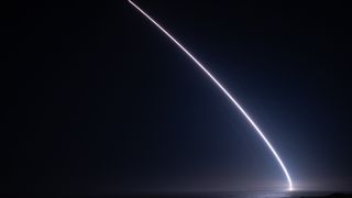 a streak of light arcs into the night sky
