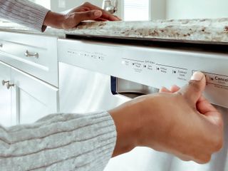 A woman pressing the button to start her dishwasher