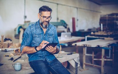 Small-business owner in his shop working on a tablet computer