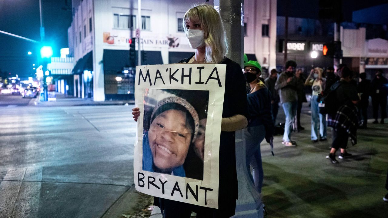 Lady on street corner wearing face mask holding post of Ma&#039;Khia Bryant