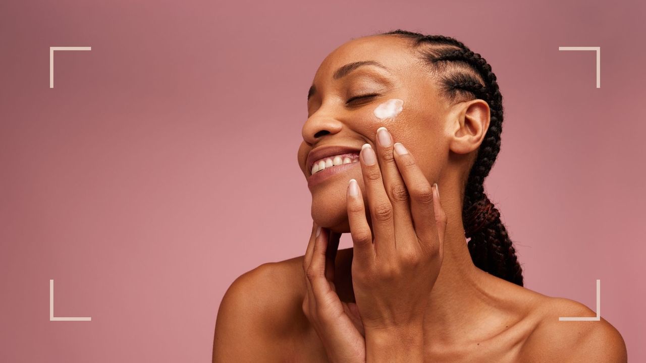 A woman using retinol on her skin on a pink backdrop