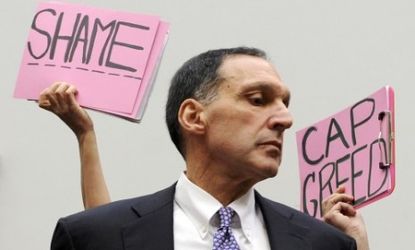 Protestors hold signs behind Richard Fuld, Chairman and Chief Executive of Lehman Bros.