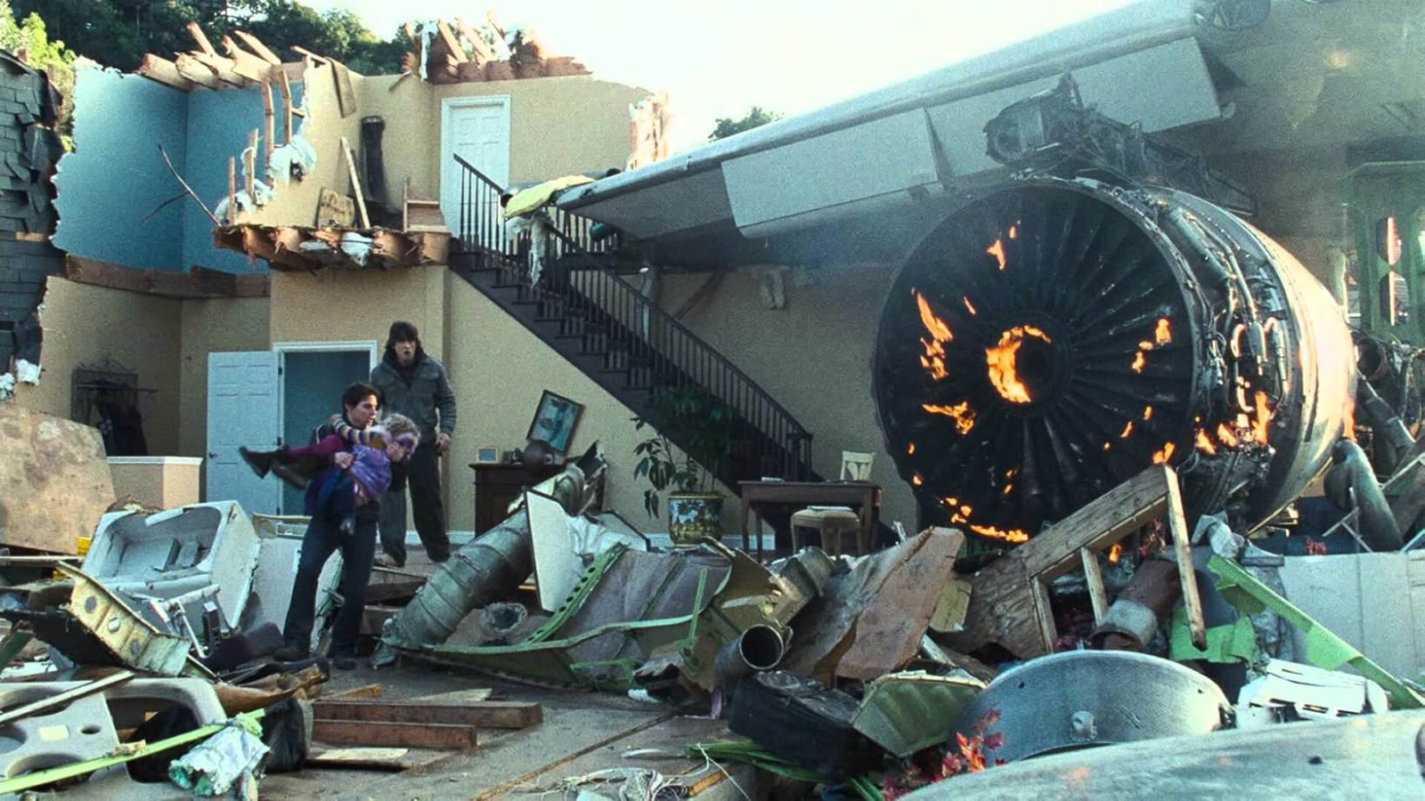 Still from the sci-fi movie "World of the Worlds" (2005). A man is carrying hi young daughter through the wreckage of a house. His teenage son is following them.