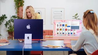 Two 24-inch iMacs in blue and pink in a school setting