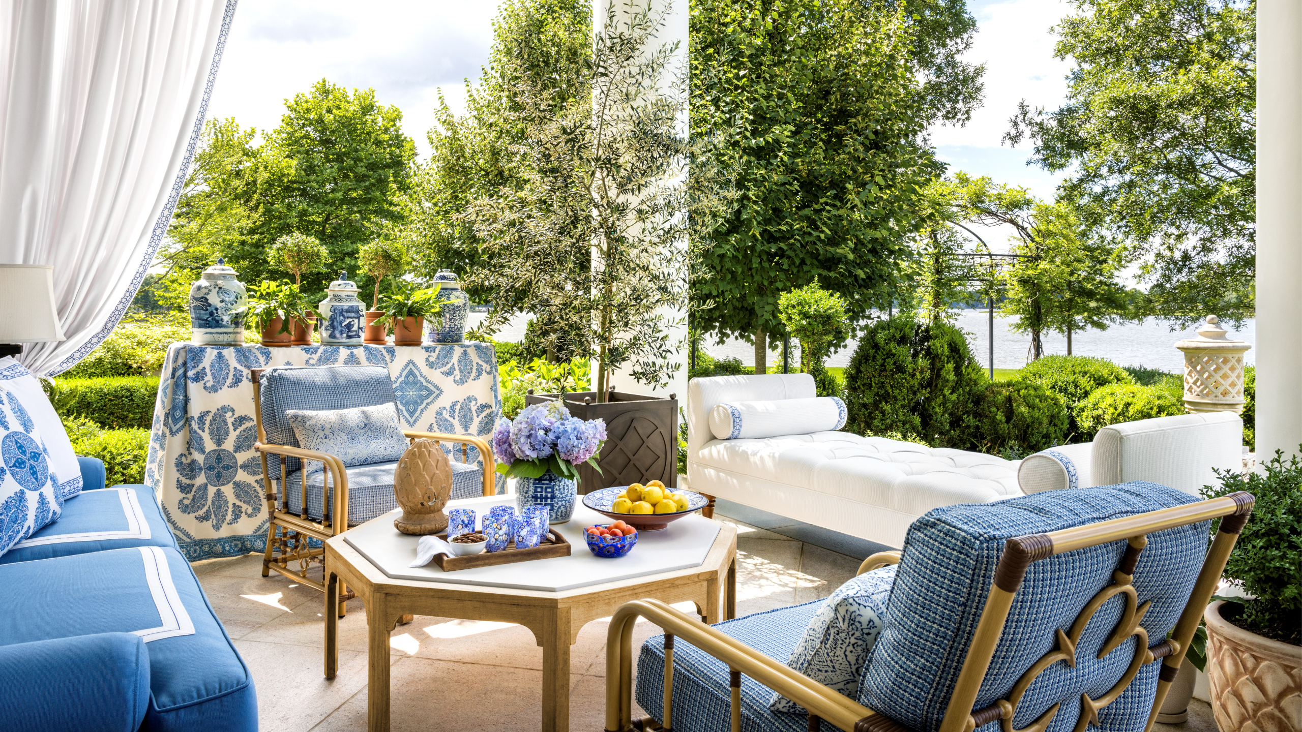Colonial Revival back patio styled by Corey Damen Jenkins, featuring light blue and white patio furniture, lighting, and textiles. 