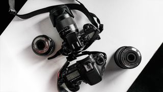 A top-down view of two DSLR cameras with different lenses on a white surface, showcasing their detailed designs and features