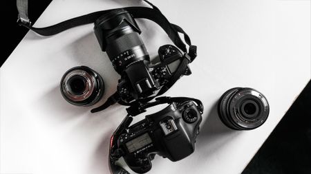 A top-down view of two DSLR cameras with different lenses on a white surface, showcasing their detailed designs and features