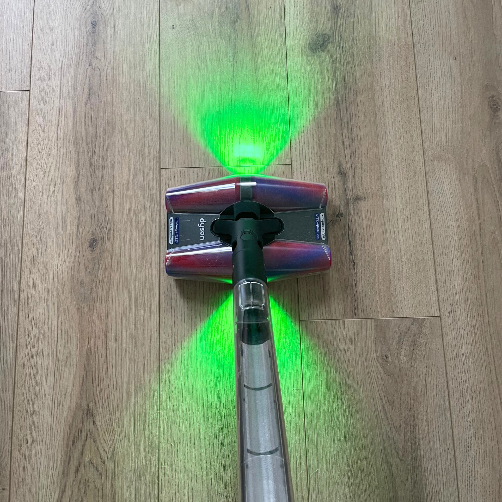 Dyson PencilVac on wood-effect flooring, with green lighting either side of the floorhead