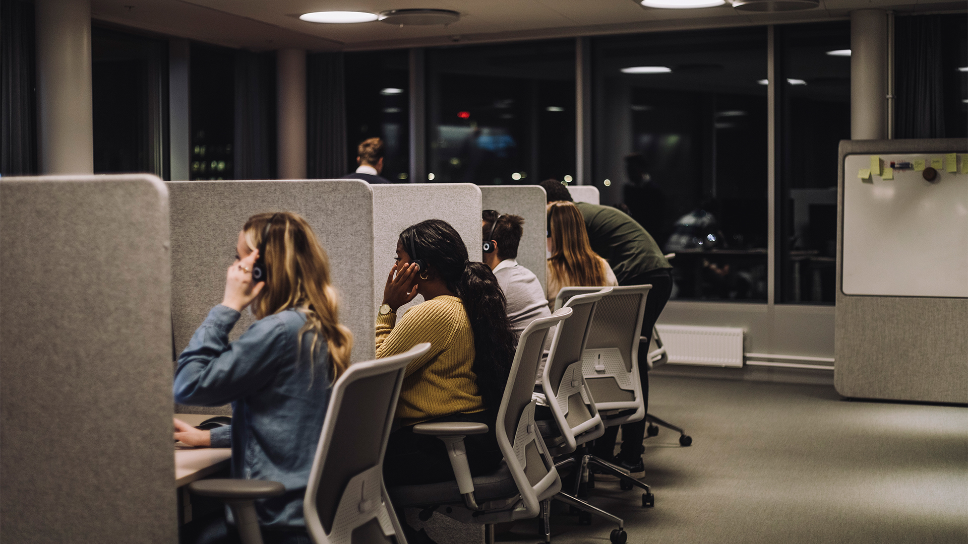 Outsourcing concept image showing workers at cubicles in open plan call center.