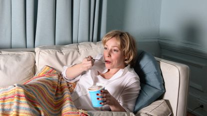 Woman eating ice-cream mindlessly while watching TV 