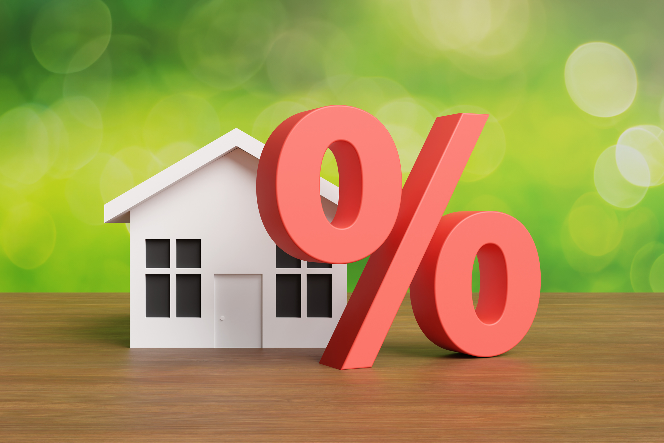 Red percentage sign in front of a white toy house on a wooden table with a green background.