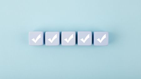 Five white checkmarks on white cubes against bright pastel blue background.