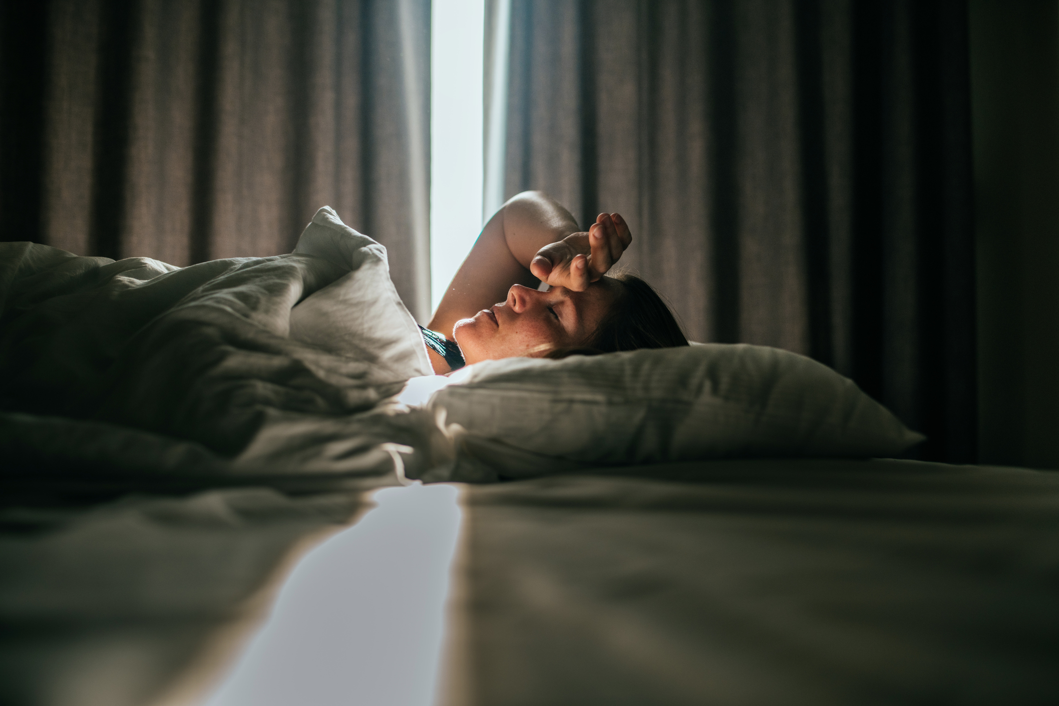Woman laying in bed with her hand on her head