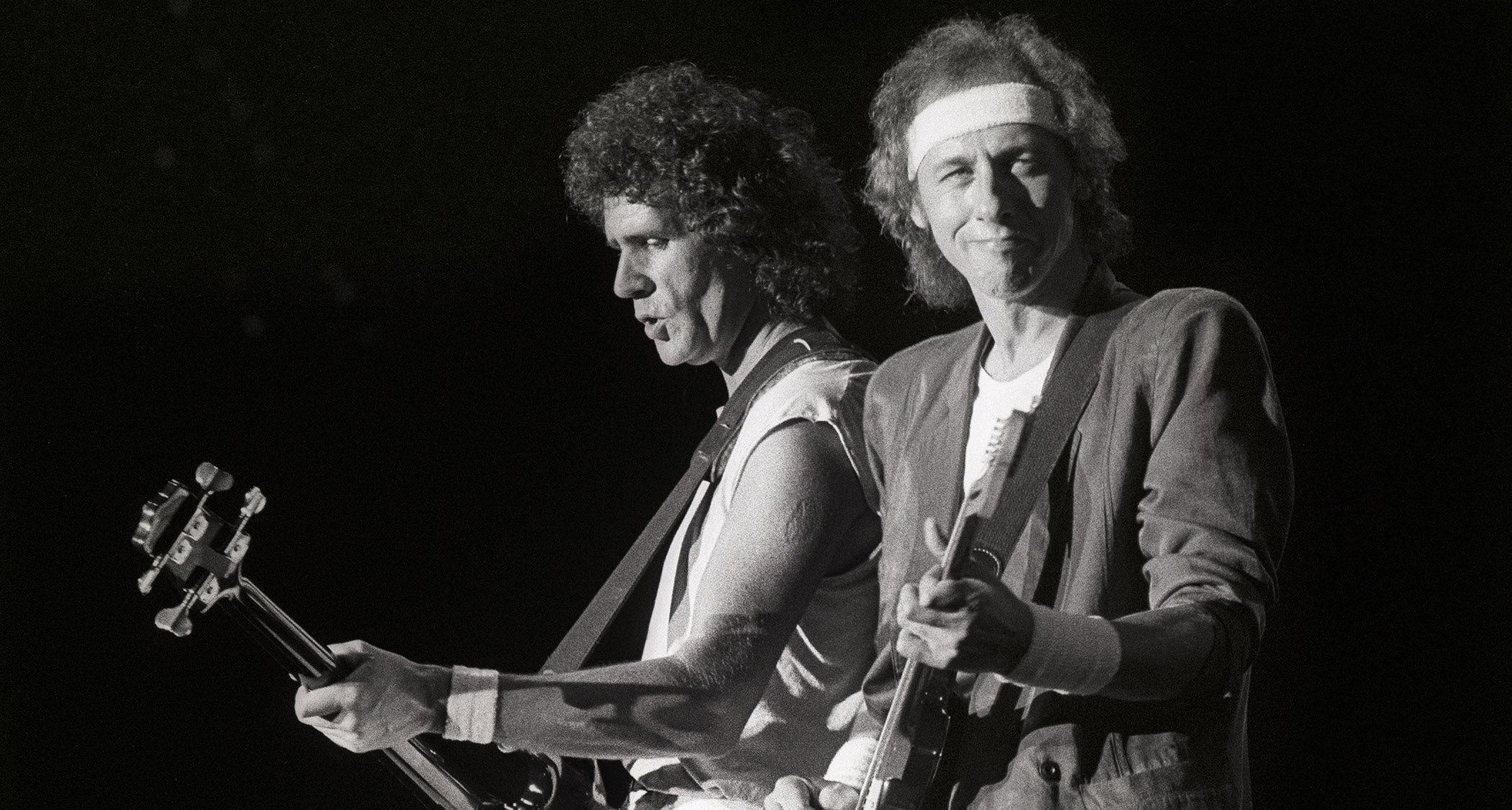 A black-and-white live shot of Dire Straits John Illsley and Mark Knopfler performing in 1985