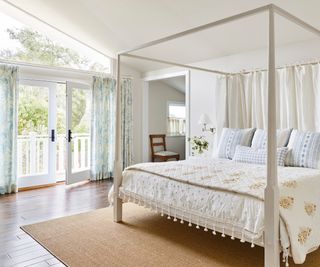 bedroom with white four poster and patio doors and balcony