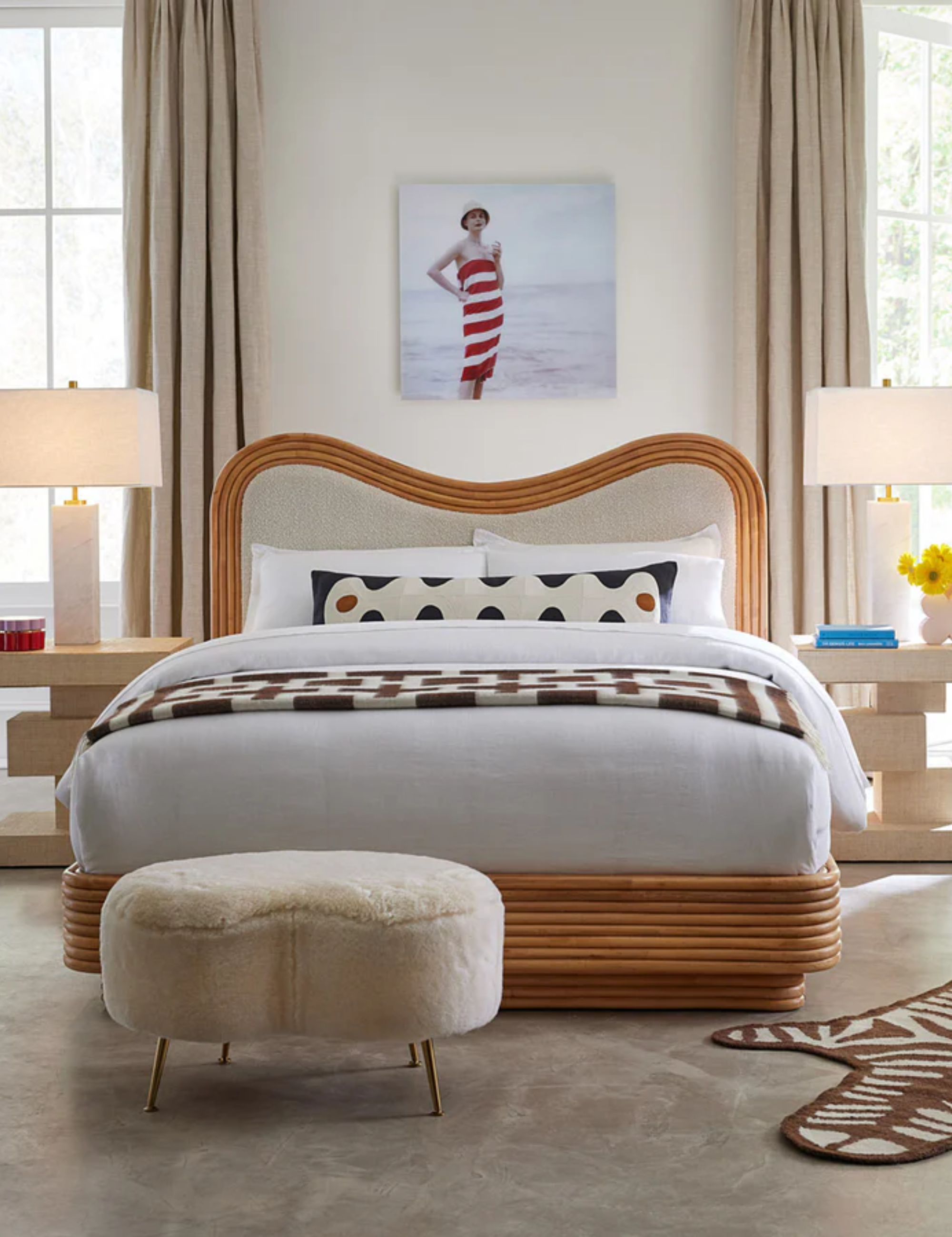 a bedroom with a wooden bedframe, a ottoman at the end of the bed, two lamps on either side, and a picture of a woman above the bed