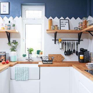 kitchen with white and blue wall wooden shelf wooden counter and wash basin