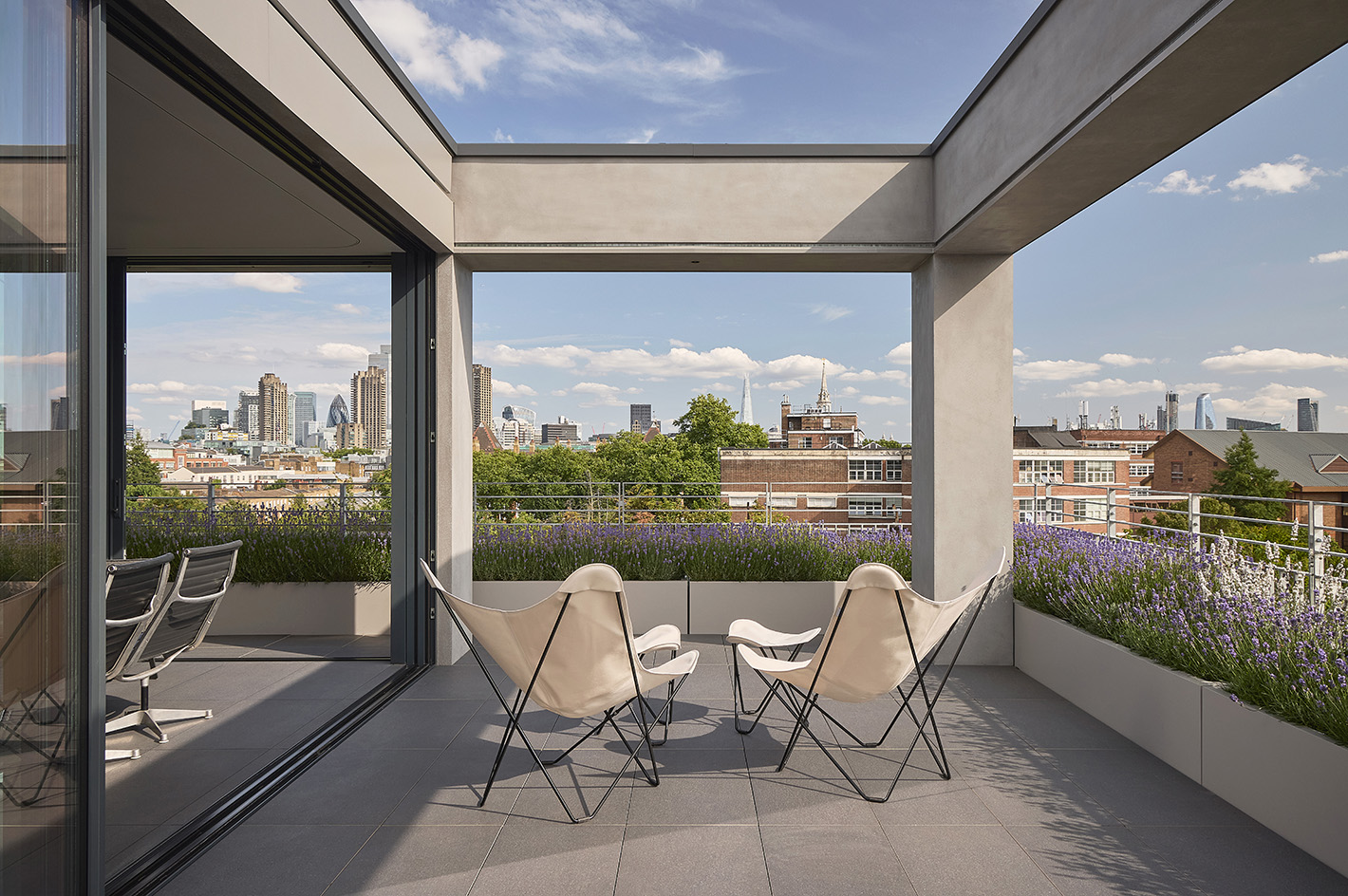Clerkenwell Rooftop apartment in London, showing minimalist concrete and large openings with terrace and views out to urban views with green