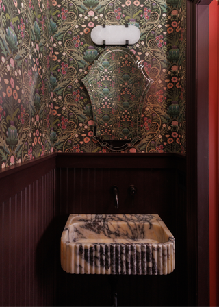 a petite bathroom with a fluted marble sink and purple walls