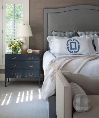 Bedroom with gray headboard, white bedding and lightly striped natural wall to wall carpet