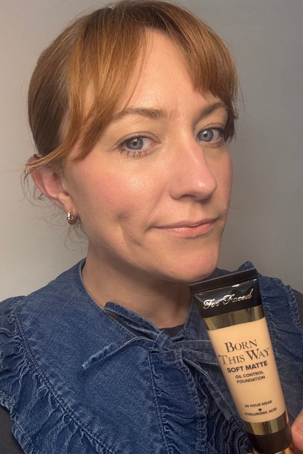 a headshot of matilda with a tube of too faced foundation