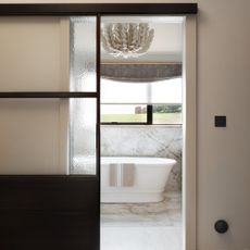 view into a neutral en suite bathroom and bath via a sliding glass door