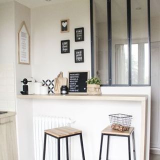 Cute coffee nook idea with breakfast bar style counter, bar stools and framed typography prints in mono palette