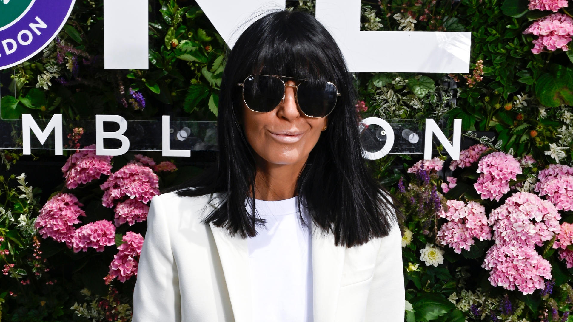 Image of Claudia Winkleman at Wimbledon 2026 with black bob and fringe, wearing sunglasses and a cream blazer