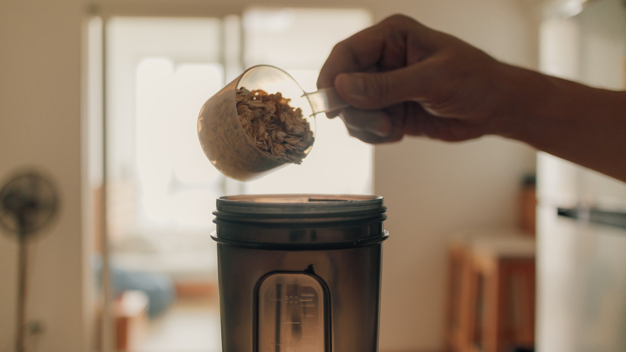 Someone pours oats into a blender