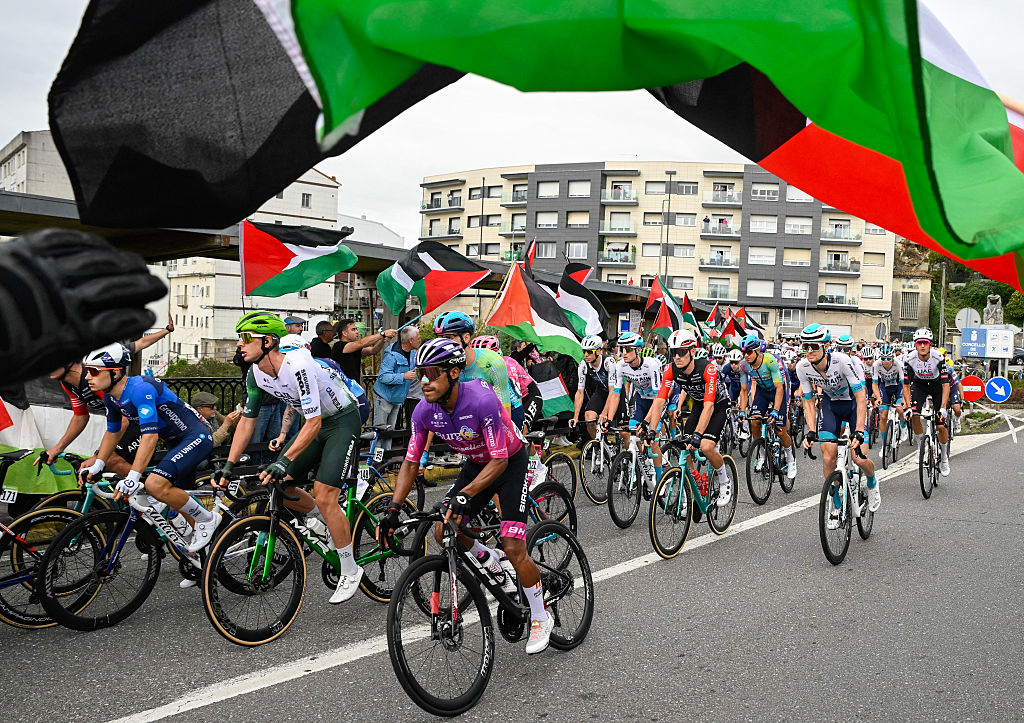 Pro-Palestinian protesters wave flags and shout as the peloton rides by in Poio at the start of the 16th stage of the Vuelta a Espana, a 172 km race between Poio and Castro de Herville, on September 9, 2025. (Photo by Miguel RIOPA / AFP) (Photo by MIGUEL RIOPA/AFP via Getty Images)