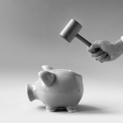 women hand using hammer trying to break a pink colour piggy bank on blue background