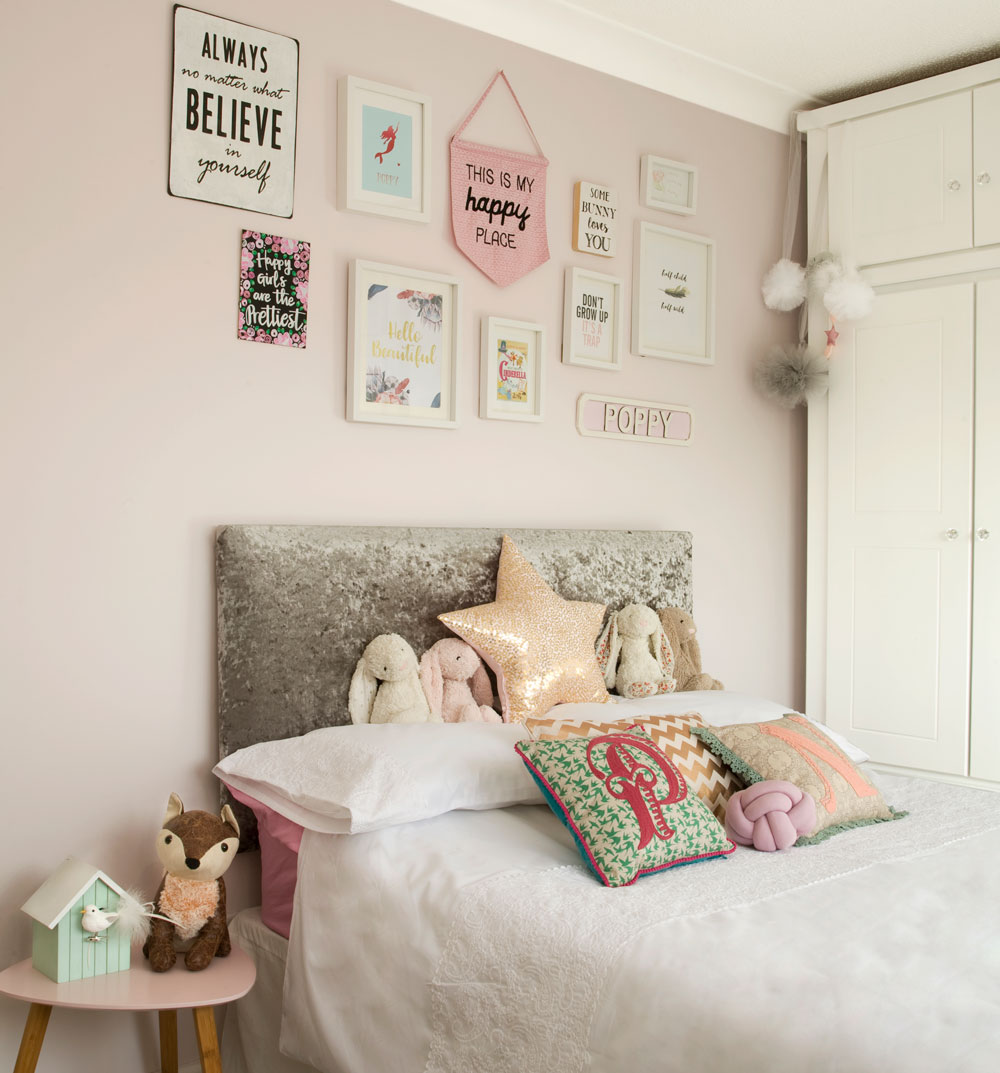 pink bedroom with bed, white cupboard and gallery wall