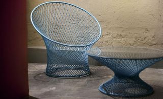 A blue wire woven chair and round table.