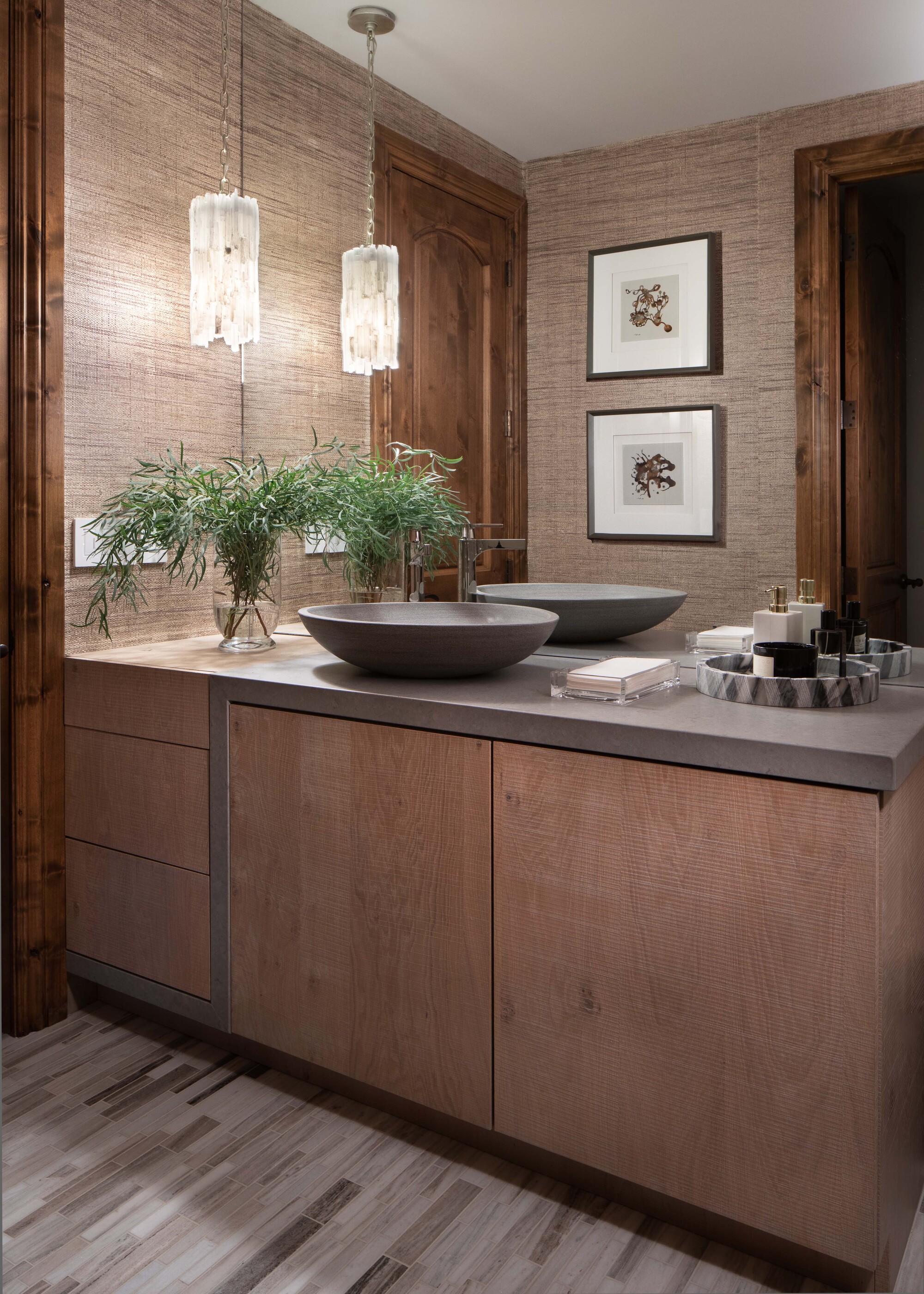 A bathroom vanity with natural wood cabinet fronts, neutral decor, and a stone sink