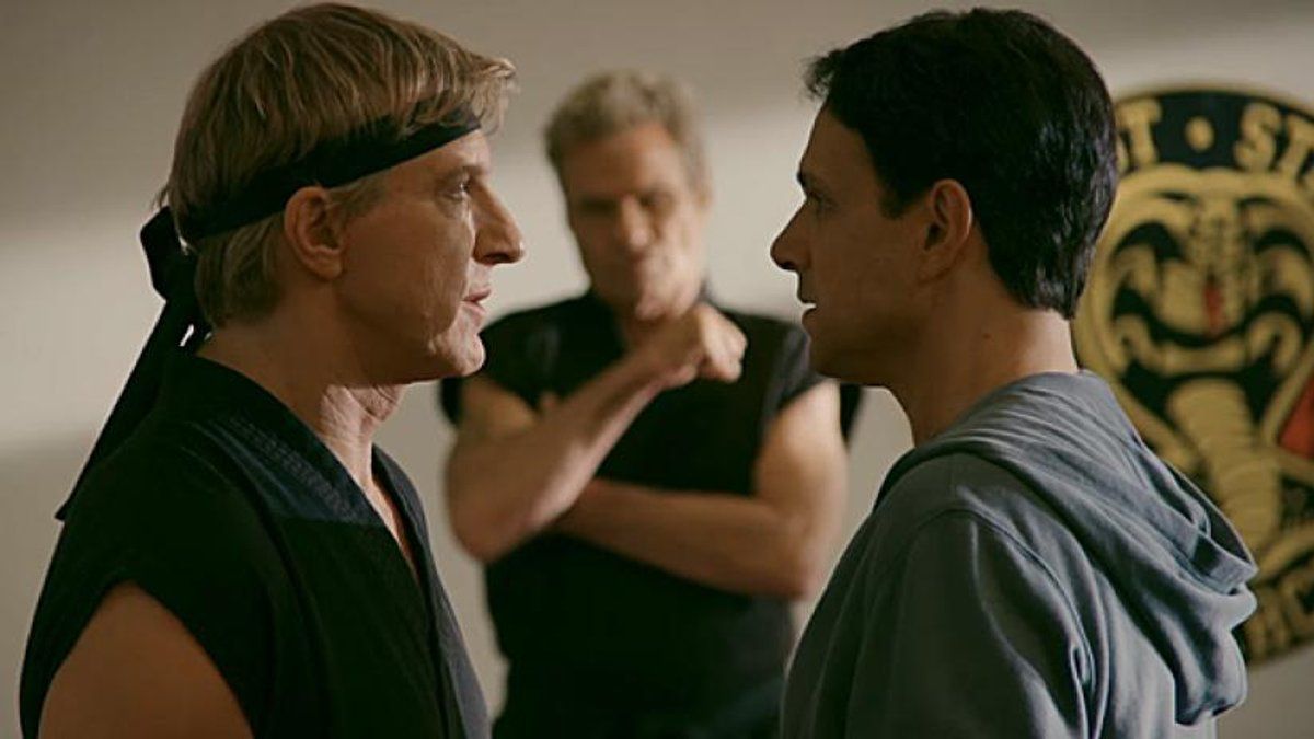 Johnny Lawrence (William Zabka) and Daniel LaRusso (Ralph Macchio) come face to face while Kreese (Martin Kove) waits for them to fight.