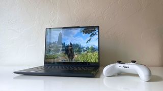 The Lenovo IdeaPad 5 2-in-1 running Enshrouded (Keen Games) next to a white game controller