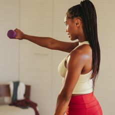Home workouts that build muscle: A woman lifting a weight
