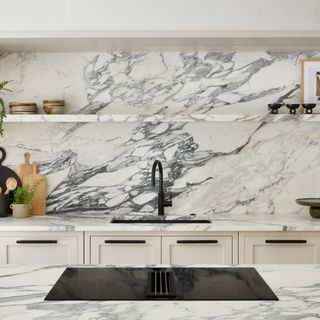 Richly veined grey and white marble splashback in a white kitchen with black tap and sink