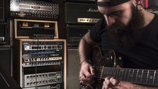 Guitarist with a beard records his electric guitar through the IK Multimedia Axe I/O audio interface