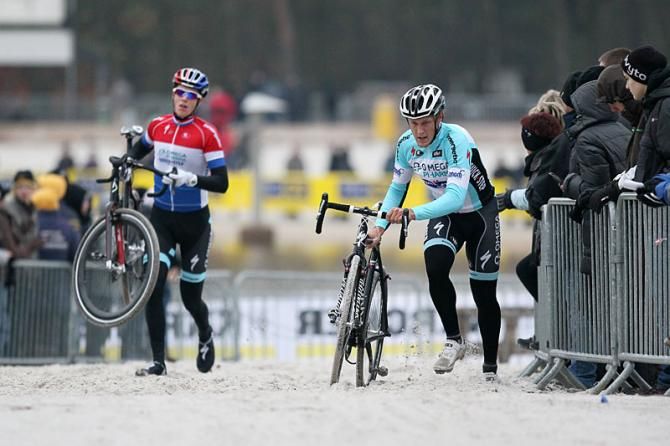 Two Omega Pharma Quick Step racers run with their bikes.