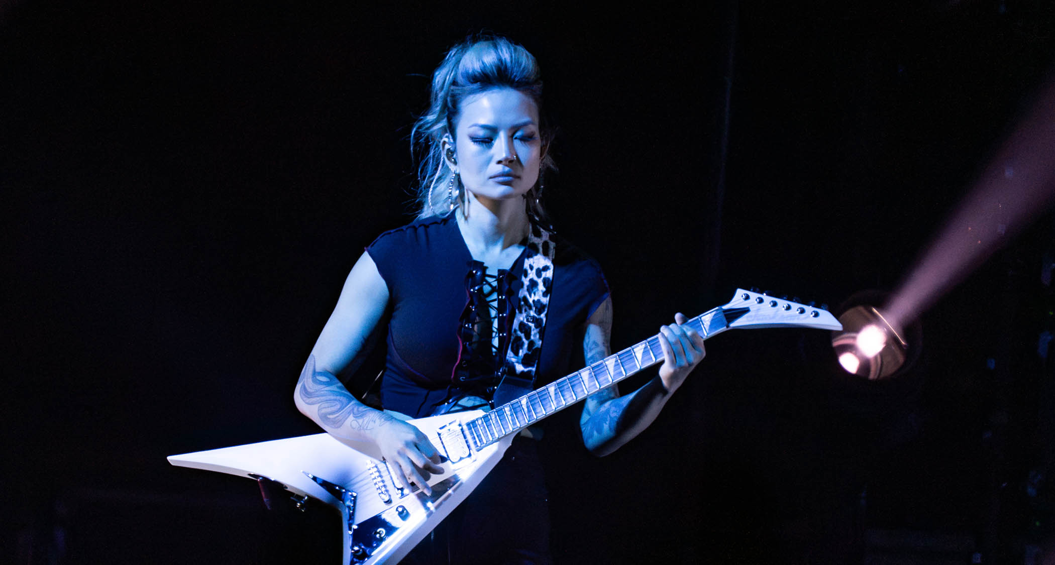 Kiki Wong plays her white Jackson Rhoads V-style electric onstage with the Smashing Pumpkins