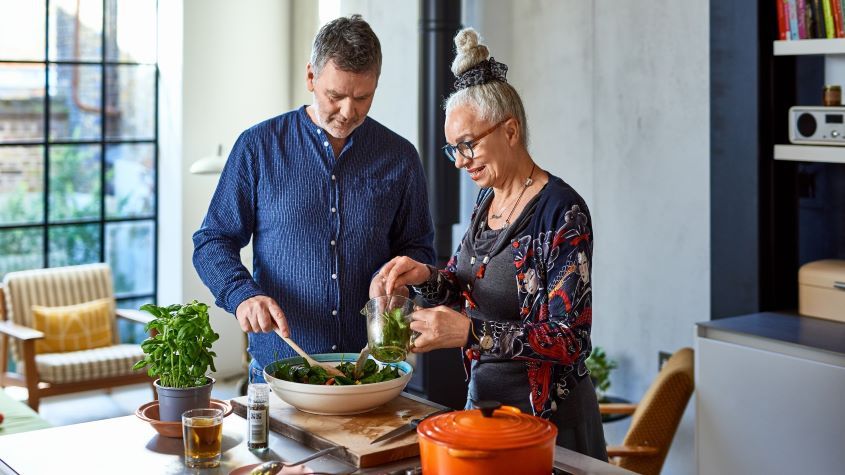 Senior man and woman making salad in a bowl