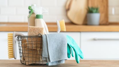 A basket of cleaning products on a kitchen counter top