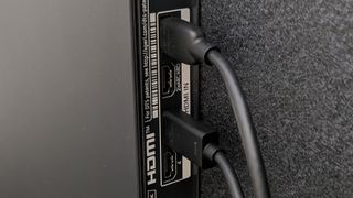 A row of HDMI ports on the back of a TV, with two cables attached in specific ports, with an empty port labelled 'HDMI ARC'