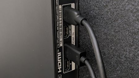 A row of HDMI ports on the back of a TV, with two cables attached in specific ports, with an empty port labelled 'HDMI ARC'