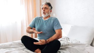 A man performs breathwork on his bed