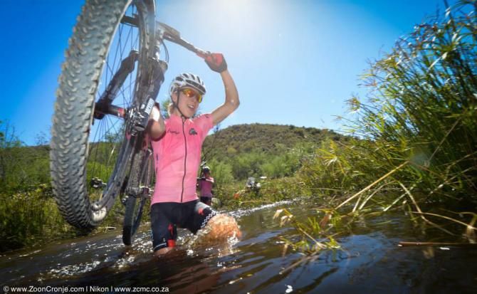 Team RE:CM Davinci's Annika Lanvad leads teammate, Ariane Kleinhans through a river during Stage 4