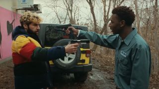 Christopher Abbott and Jerrod Carmichael aim guns at each other behind a strip club in On The Count Of Three.