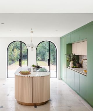 Large family kitchen with curved island and green cabinetry